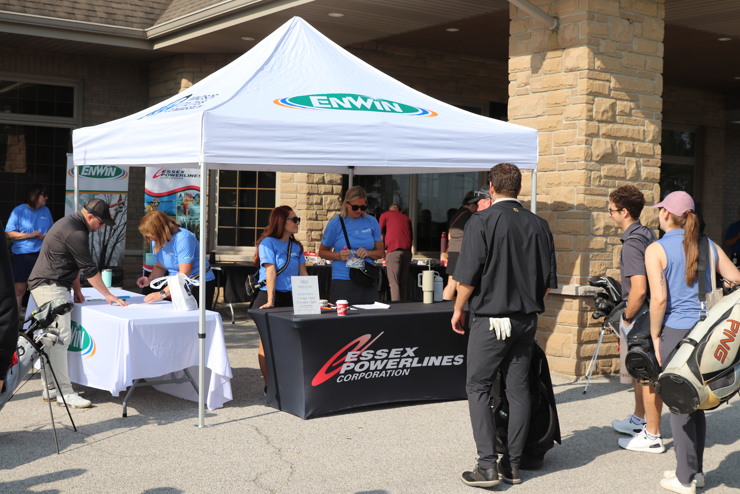 A golf tournament sign up tent with enwin and essex power logos