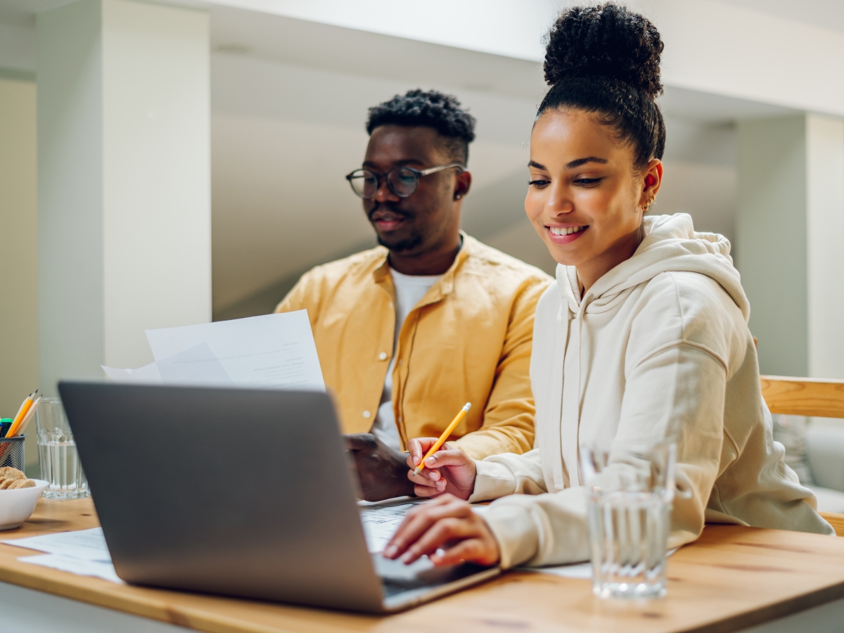 couple paying bills in front of laptop and holding paper